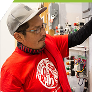 An indigenous student checks a circuit panel in the electrical shop. 