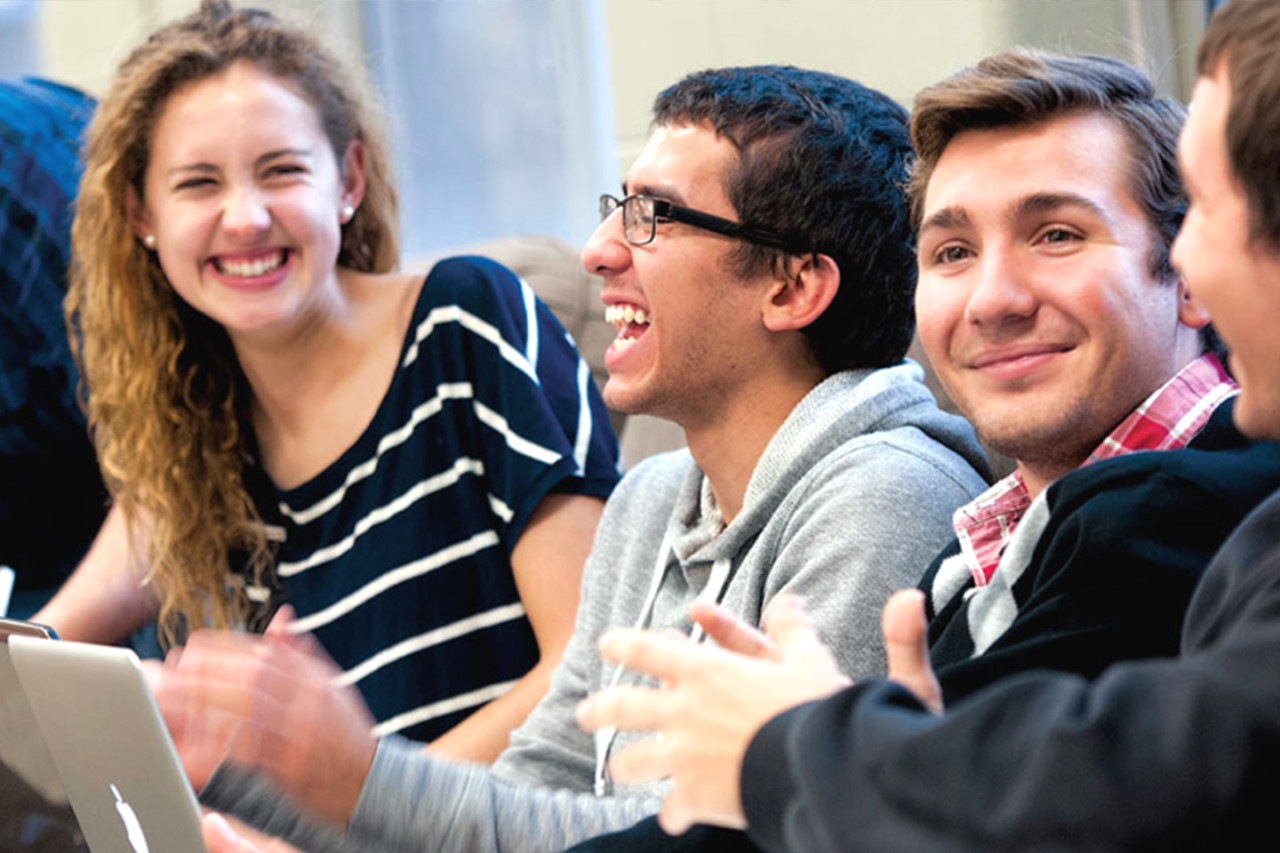 A group of students laughing with each other in class